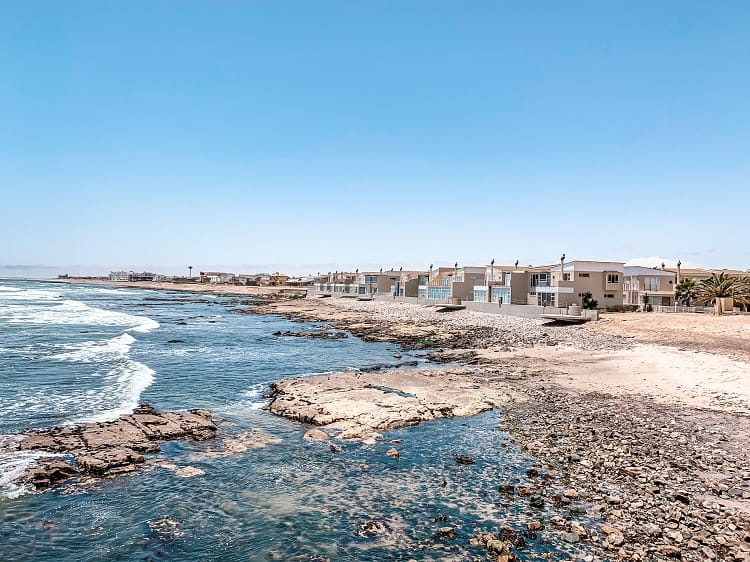 Where to Stay in Swakopmund in Namibia, photo of the rocky coastline and residential two story buildings 