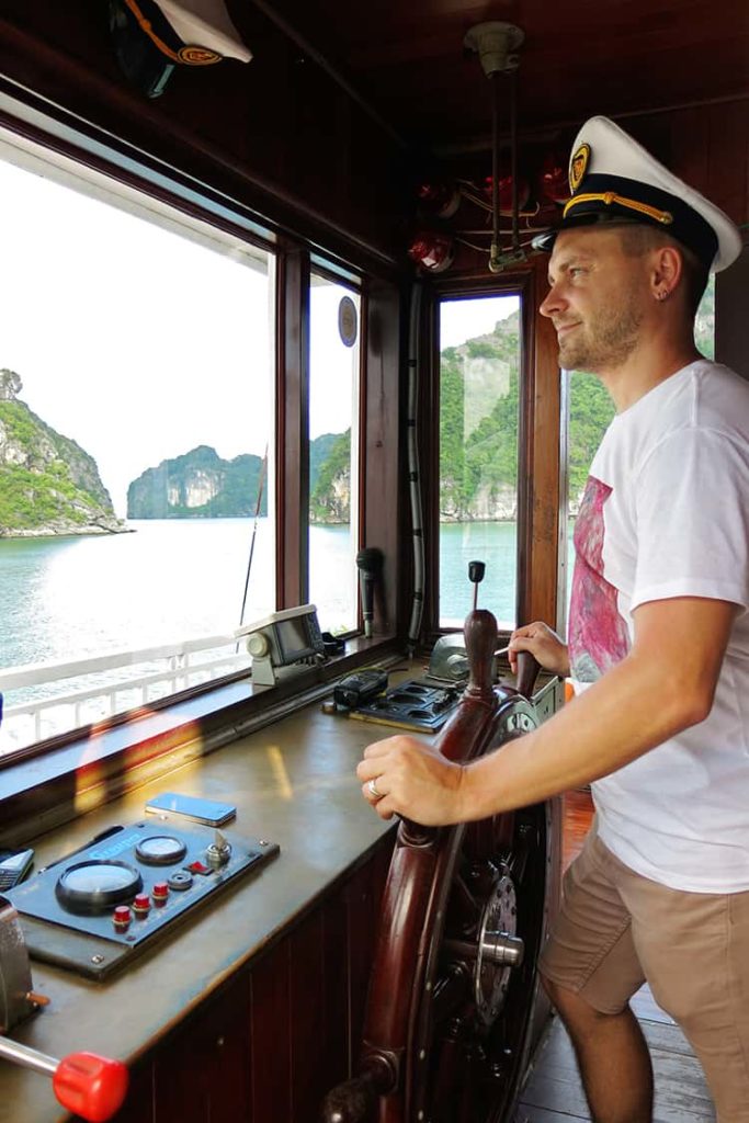 Captain holding a steering wheel-of-Indochina-Junk-Sails-Cruise, Halong Bay Vietnam