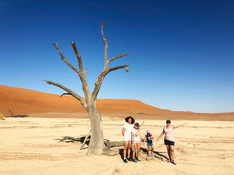 Deadvlei in Sossusvlei Namibia, mother and three daughters posing for a photo next to a dead tree, sand dune in background