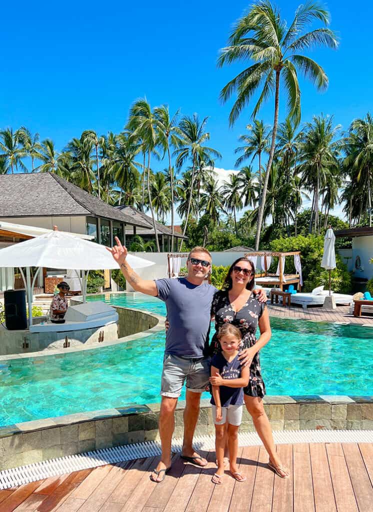 Beach Club in Koh Samui, Thailand, family standing in front of the pool, palm trees, DJ playing music in the background