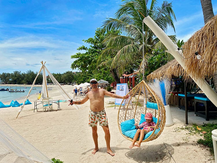 Choegmon beach on koh samui, Thailand, father standing, daughter sitting in a swing chair