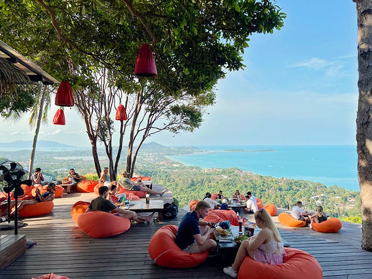 Jungle Club Koh Samui, Thailand, people sitting on orange bean bags, eating food and having drinks, whilst enjoying the view of the island and the ocean