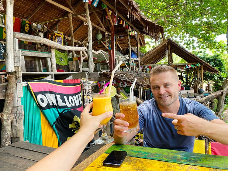 Drinks at Rock Cafe in Lamai, Koh Samui, Thailand, man cheers with cocktails, rustic wooden reggae bar in the background