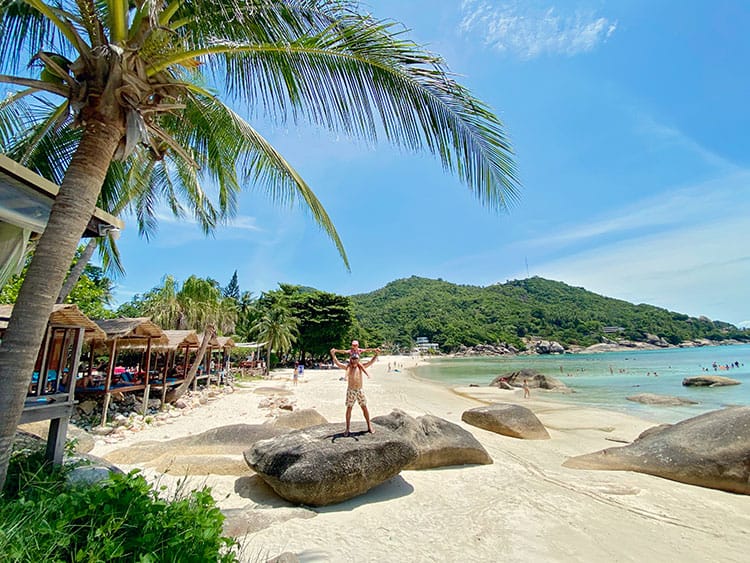 Silver Beach, Koh Samui, Thailand, father and daughter standing on the rock with beach in background, palmtree 
