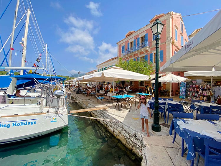 Fiskardo in Kefalonia, Greece, young girl at the old port, restaurants and boats