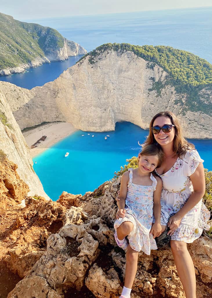 Best things to do in Zakynthos - Navagio Shipwreck Beach lookout, mother and daughter sitting on the rocky edge