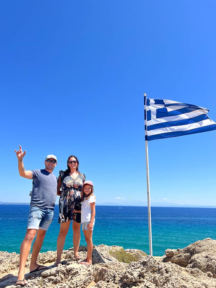 Things to do in Zakynthos Greece - Agios Nicholaos Chapel, family on the rock with the Greek Flag