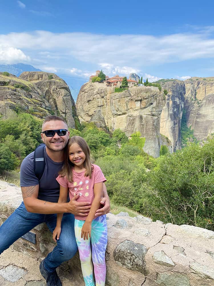 Holy Trinity Monastery Meteora, Greece, father and daughter sitting, monastery in the background