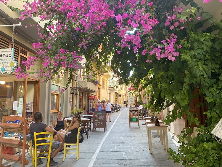 Family Vacation to Crete, Greece, Rehymnon Old Town, alley view of restaurants and trees with pink flowers