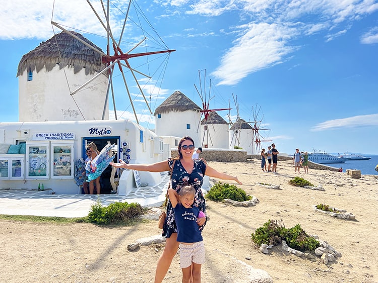 Mykonos in September - Mykonos Windmills, mother and daughter arms up in front of the windmills, Greece