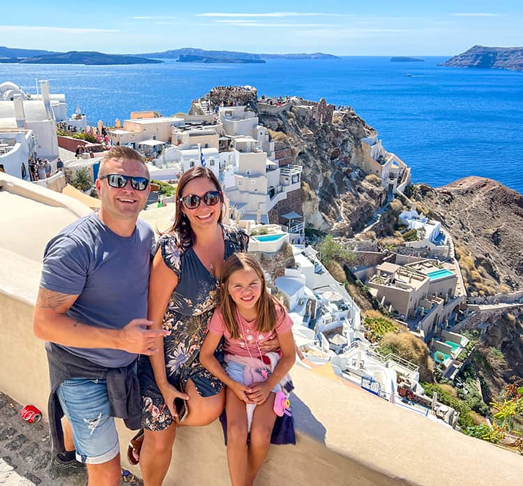 Santorini in September, Greece - Oia Santorini, family posing for a photo, buildings and ruins of the castle in the background