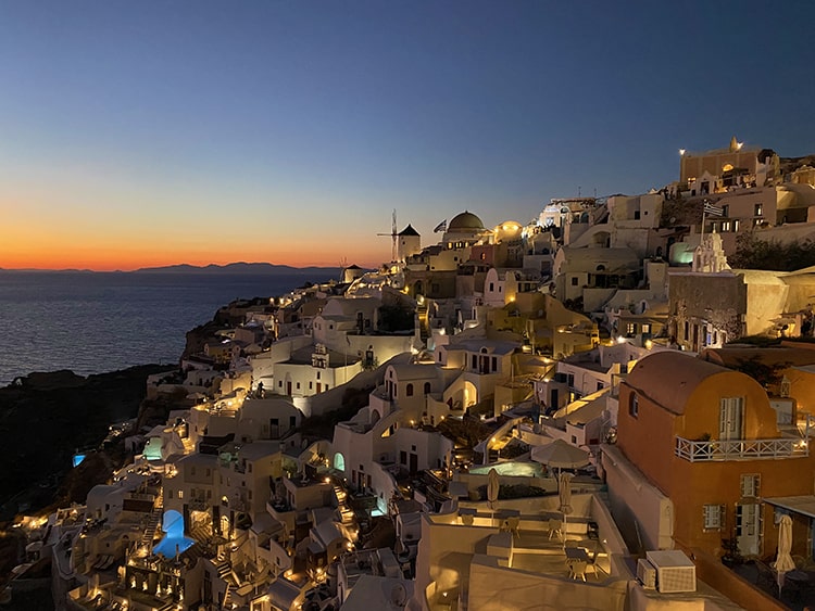 Santorini in September, Greece - Oia at night, evening view of the buildings, lights and sunset