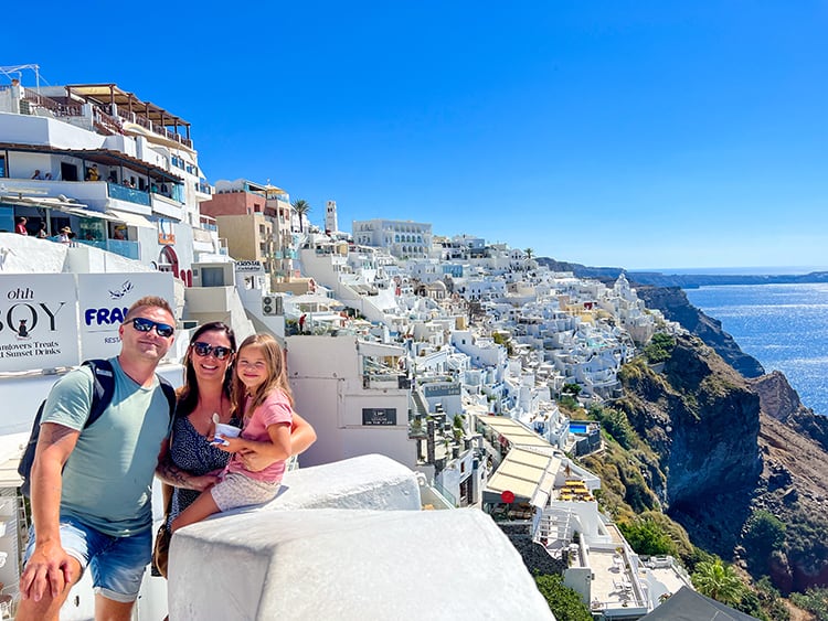 Santorini in September, Greece - family at the view point at Fira Santorini, white buildings on the edge of the cliff, water down below