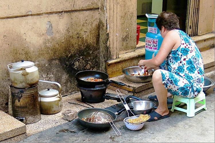 Best Walking Tours in Hanoi, lady cooking on the side of the walkway
