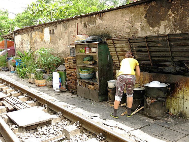 Best Walking Tours in Hanoi, lady cooking on the side of train track