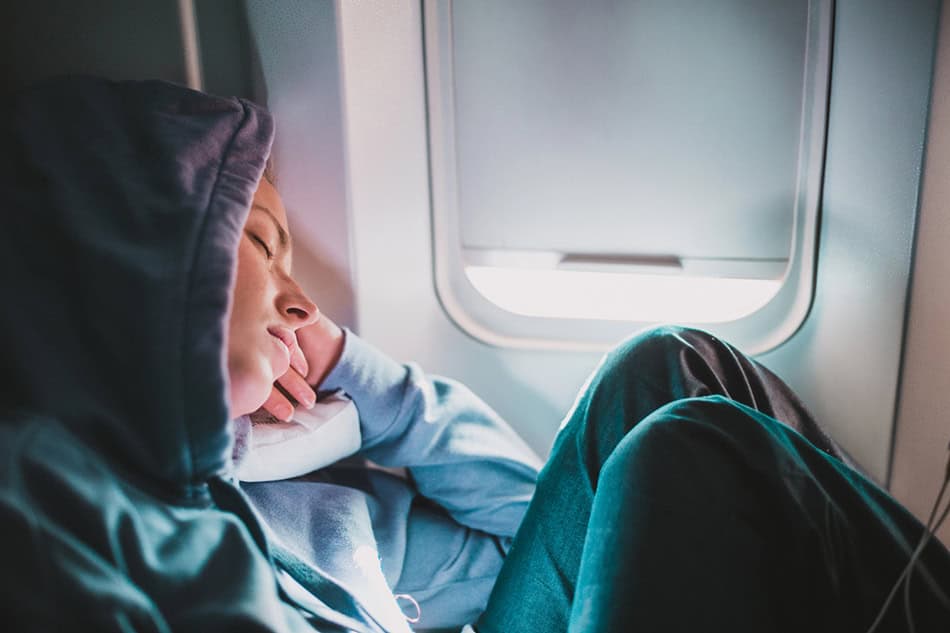 On a plane in a hoodie sleeping